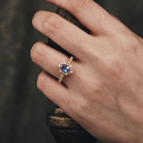 Oval Alexandrite engagement ring with floral moissanite accents on twisted gold band.